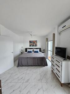 a white bedroom with a bed and a television at Suíte en apartamento privado in Balneário Camboriú