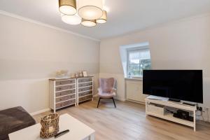 a living room with a flat screen tv and a chair at Ferienwohnung Leuchtfeuer in Brodten