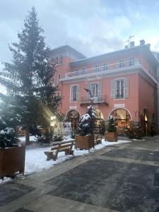a large pink building with a christmas tree in front of it at À louer beau deux-pièces St-Etienne-de-Tinée in Saint-Étienne-de-Tinée