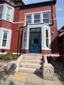 a brick house with a blue door and stairs at Mode Cottage in Lytham St Annes