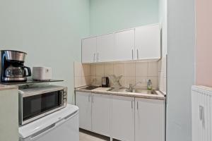 une cuisine blanche avec un évier et un micro-ondes dans l'établissement Apartment Uthman Berlin-Neukölln, à Berlin