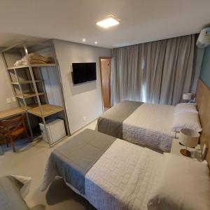 a hotel room with two beds and a television at Pousada Infinity Gasthaus in Pomerode +13 photos