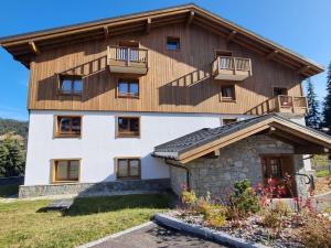 ein Haus mit einem Holzdach und einem Balkon in der Unterkunft Appartement luxueux 3 pièces, spa privé, skis aux pieds - FR-1-810-21 in Les Saisies