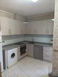 a kitchen with white cabinets and a washing machine at Apartamento Bela Vista em Castro Daire in Castro Daire
