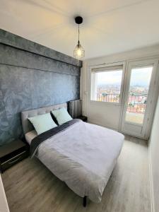 a bedroom with a large bed and two windows at Chambre tout confort in Tarbes
