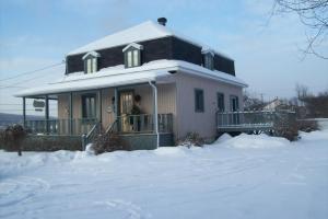 a house with snow on the ground in front of it at La Belle Époque in La Malbaie
