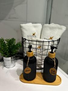 two black bottles sitting on a table with a basket of towels at Apartman Njegoš Lux Titova vila in Palisad