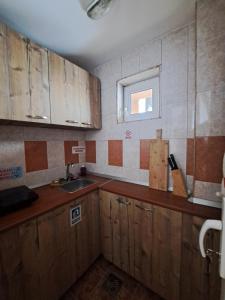 a kitchen with wooden cabinets and a sink and a window at Pensiunea Vladis in Lupeni