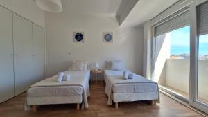 two beds in a room with a large window at Apartamentos Jardim do Morro in Vila Nova de Gaia