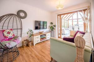 a living room with a couch and a tv at Sunset Garden Cottage, Reydon in Reydon