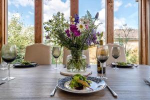 a table with a vase of flowers and plates of food at Sunset Garden Cottage, Reydon in Reydon