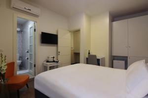 a bedroom with a large white bed and a bathroom at Idelson Hotel in Tel Aviv
