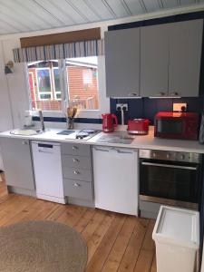a kitchen with white cabinets and a red appliance at Chalet 24 in Seaton +4 photos