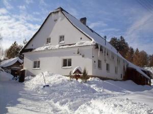a large white house with snow on the ground at Penzion Kučera apartmán in Dolní Moravice