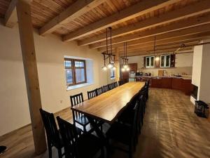 Habitación grande con mesa de madera larga y sillas. en Chalupa Netopýr, en Černá Voda