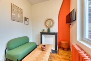 un soggiorno con un divano verde e una televisione di Emma Mignon F2 proche de la gare a Rouen