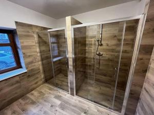 y baño con ducha y paredes de madera. en Chalupa Netopýr, en Černá Voda