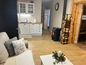 a living room with a white couch and a kitchen at ACTIVFARM DOMKI NA KASZUBACH Domek Dorotka in Gliśno