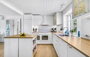 Una cocina con gabinetes blancos y una encimera de madera. en Eight-Bedroom Holiday Home In Norre Nebel, en Nørre Nebel