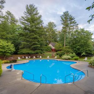 a large blue pool with chairs and trees at Highland Lake Inn & Resort - Flat Rock in Flat Rock