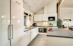 una cucina con mobili bianchi e un piano di lavoro di Cozy Home In Nørre Nebel With Sauna a Nørre Nebel