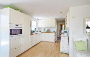 a kitchen with white cabinets and a wooden floor at Lovely Home In Juelsminde With Kitchen in Sønderby