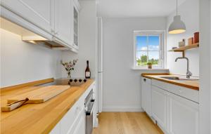 a kitchen with white cabinets and a wooden counter top at 3 Bedroom Awesome Home In Vejby in Vejby