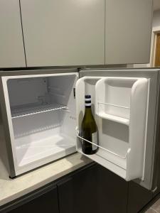 an open refrigerator with a bottle of wine in it at Cotswold Retreat in Cheltenham