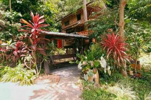 un giardino con una casa con piante di fronte di Bangtao Wooden house resort and cafe a Ban Thalat Choeng Thale