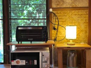 un forno a microonde seduto su un tavolo accanto a una lampada di Bangtao Wooden house resort and cafe a Ban Thalat Choeng Thale