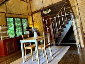 una sala da pranzo con tavolo, sedie e scala di Bangtao Wooden house resort and cafe a Ban Thalat Choeng Thale