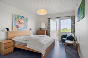a bedroom with a large bed and a chair at Sct Knudsborg - 12C - Apartment on the beach in Brenderup