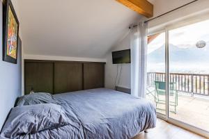 a bedroom with a bed and a large window at Les 5 Vallées - Appt en Duplex avec vue montagne in Briançon