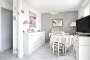 a white dining room with a table and a tv at Les balcons des Ecréhous - Duplex front de mer in Saint-Jean-de-la-Rivière