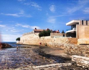 a group of people walking on a beach next to a stone wall at Faber Apartments in Novigrad Istria