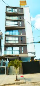 a tall building with a palm tree in front of it at Hamptons João Pessoal in João Pessoa