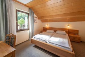 a bedroom with a bed and a desk and a window at Café Pension Leistner in Obertrubach