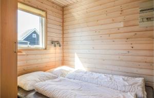 a bed in a wooden room with a window at Hytte 25 in Thyborøn