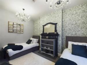 a bedroom with two beds and a mirror and chandelier at Montague House Town Centre Sleeps Up To 12 Guests in Ross on Wye