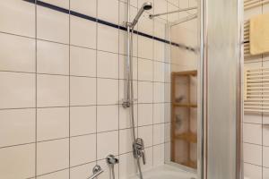 a shower in a bathroom with white tiles at Ferienwohnung Tannenblick 2-1 in Oberhof +17 photos