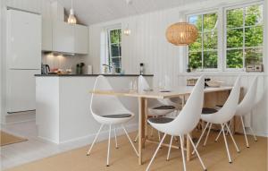 Una cocina con una mesa de madera y sillas blancas. en Amazing Home In Gilleleje With Wifi, en Gilleleje