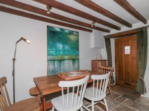 Un comedor con mesa y sillas de madera. en Meadow View Cottage, en Cheltenham