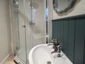Un baño con lavabo y ducha de cristal. en Meadow View Cottage, en Cheltenham