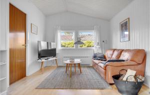 a living room with a leather couch and a television at 2 Bedroom Beautiful Home In Gilleleje in Gilleleje