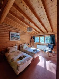 a bedroom with two beds and a chair in a room at Our Log House in the woods in Balnald