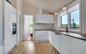 a kitchen with white cabinets and a large window at Lovely Home In Løkken With Sauna in Løkken