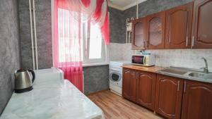 a kitchen with a sink and a window with pink curtains at КУБА Апартаменты 1-ком в центре in Petropavlovsk