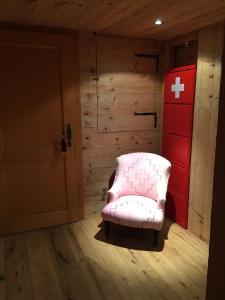 einen rosa Stuhl in einem Zimmer mit einer roten Wand in der Unterkunft The Chalet in Gstaad