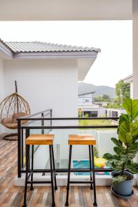 a balcony with a glass table and two stools at BUDDe' Cozy House วิลล่าอบอุ่น&ใกล้เมืองใกล้ทะเล in Hua Hin