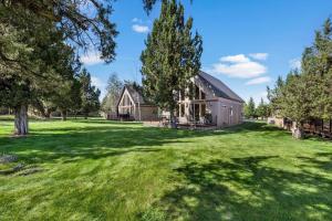 a large barn in a field with trees and grass at Oregon Chalet in Redmond